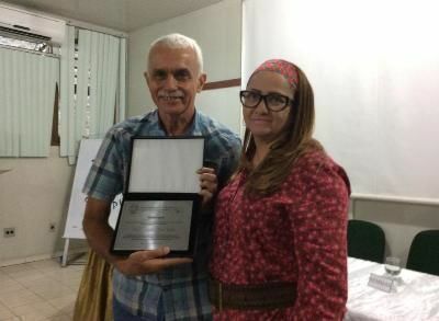 A diretora do CCA entrega a placa de homenagem ao professor Antonio Webber
